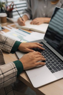 Bir iş kadını ekibine bilgi göndermek için elektronik bir cihaz kullanıyor. Pazarlama ekibi lideri, pazarlama verileriyle ilgili belgeleri inceliyor.