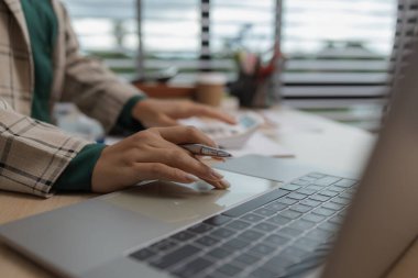 Bir çalışan, zamanında tamamlanması gereken belgelerle dolu bir ofiste oturur ve pazarlama ekibi lideri, pazarlama bilgileriyle ilgili belgeleri gözden geçirir.