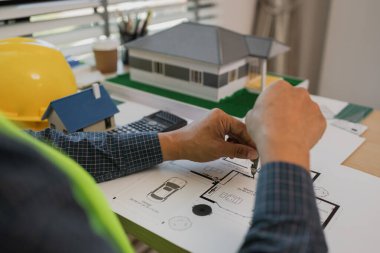 Ofiste çalışan bir evin modeline sahip iş adamı ya da mimar, planlarla ofiste çalışan mimar, mimari planı inceleyen mühendis, bir inşaat projesi çizen, iş konsepti,
