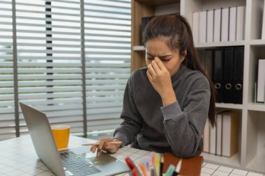 Ofisinde dizüstü bilgisayarı olan yorgun genç bir kadın, iş kadını, son teslim tarihi için ofiste stres, beyin sisi ve fazla mesai, yorgunluk ve yönetim için bunalmış