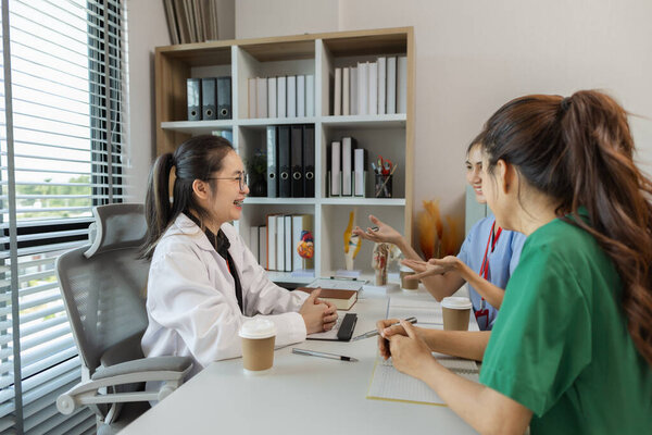 the three doctors are meeting to exchange new knowledge and information they have gained form their medical seminars with each other, a senior doctor is explaining information and knowledge