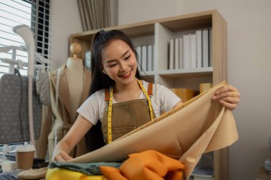 Güzel bir terzi, çeşitli dikiş malzemeleri, kumaş ve ipliklerle dolu bir stüdyoda en sevdiği zanaat üzerinde çalışıyor. Tasarımcı, terzi, moda, girişimci.