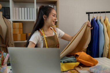 Güzel bir terzi, çeşitli dikiş malzemeleri, kumaş ve ipliklerle dolu bir stüdyoda en sevdiği zanaat üzerinde çalışıyor. Tasarımcı, terzi, moda, girişimci.