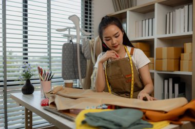 Güzel bir terzi, çeşitli dikiş malzemeleri, kumaş ve ipliklerle dolu bir stüdyoda en sevdiği zanaat üzerinde çalışıyor. Tasarımcı, terzi, moda, girişimci.
