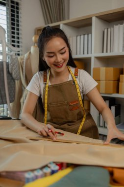 Güzel bir terzi, çeşitli dikiş malzemeleri, kumaş ve ipliklerle dolu bir stüdyoda en sevdiği zanaat üzerinde çalışıyor. Tasarımcı, terzi, moda, girişimci.