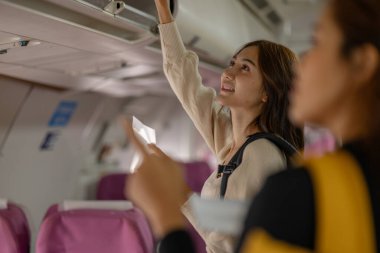 İki güzel bayan arkadaş uçakla yurt dışına seyahat ediyor, koltuklarını bulmak için yürüyorlar ve çantalarını yukarıdaki kompartımana, yolcuya, uçağa, tatile çıkıyorlar.