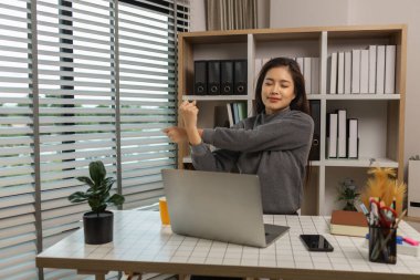 Evde esneyen ve çalışan bir kadın, masasında dinlenen güzel bir kadın, ev ofisinde dinlenen ve dinlenen, sakin ve kişisel bakım için çalışan profili olan, kollarını başınızın üstüne uzatan bir iş kadını.