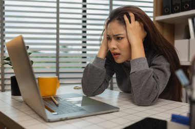 Ofisinde dizüstü bilgisayarı olan yorgun genç bir kadın, iş kadını, son teslim tarihi için ofiste stres, beyin sisi ve fazla mesai, yorgunluk ve yönetim için bunalmış