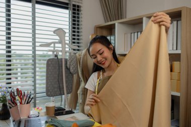 Güzel bir terzi, çeşitli dikiş malzemeleri, kumaş ve ipliklerle dolu bir stüdyoda en sevdiği zanaat üzerinde çalışıyor. Tasarımcı, terzi, moda, girişimci.