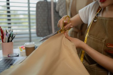 Güzel bir terzi, çeşitli dikiş malzemeleri, kumaş ve ipliklerle dolu bir stüdyoda en sevdiği zanaat üzerinde çalışıyor. Tasarımcı, terzi, moda, girişimci.