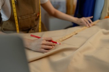 Güzel bir terzi, çeşitli dikiş malzemeleri, kumaş ve ipliklerle dolu bir stüdyoda en sevdiği zanaat üzerinde çalışıyor. Tasarımcı, terzi, moda, girişimci.