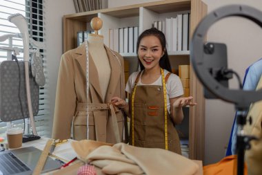 Kadın moda tasarımcısı, tasarımlarını müşterilerine canlı yayında izleterek müşterilerin satın alma kararlarını almalarına yardımcı olmak için tasarımlarının detaylarını anlatıyor.