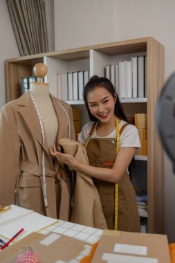 Kadın moda tasarımcısı, tasarımlarını müşterilerine canlı yayında izleterek müşterilerin satın alma kararlarını almalarına yardımcı olmak için tasarımlarının detaylarını anlatıyor.