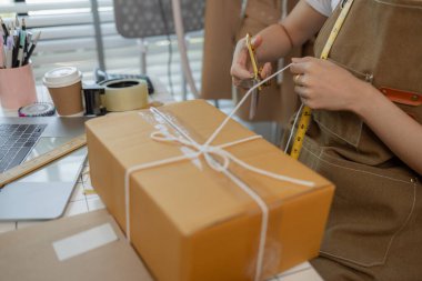 Güzel bir kadın giyim mağazası sahibi müşterilerle sohbet etmek için canlı yayın yapıyor ve ürünlerini müşterilere, paketlere, terzilere, tasarımcılara nakliyeye hazırlanmak için doxlara dolduruyor.