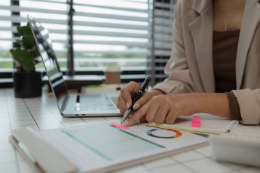 Bir iş kadını masasında oturmuş kontrol edilecek bir sürü evrakla birlikte çalışıyor. Takım lideri birçok pazarlama belgesini inceledi.