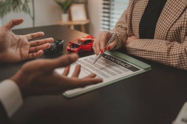 Bir araba satıcısı, satış sözleşmesini imzalamadan önce araba satın alma sözleşmesinin detaylarını müşteriye açıklar. Galeri, satıcı, araba sözleşmesi, araba satın alma sözleşmesi.