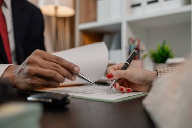 Bir araba satıcısı, satış sözleşmesini imzalamadan önce araba satın alma sözleşmesinin detaylarını müşteriye açıklar. Galeri, satıcı, araba sözleşmesi, araba satın alma sözleşmesi.