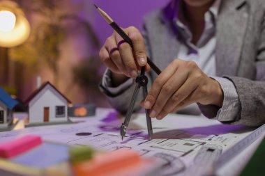 Güzel bir kadın mimar özel ofisinde çalışıyor çünkü kanunlara, mühendislere, ustabaşına ve müteahhitlere uygun olması için planların geliştirilmesine konsantre olması gerekiyor.