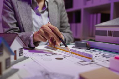 Güzel bir kadın mimar özel ofisinde çalışıyor çünkü kanunlara, mühendislere, ustabaşına ve müteahhitlere uygun olması için planların geliştirilmesine konsantre olması gerekiyor.