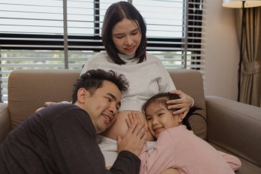 Güzel bir aile evlerinde birlikte vakit geçirir. Hamile bir anne, kocası ve kızıyla birlikte kanepede oturur ve hafta sonları birlikte mutlu vakit geçirir.