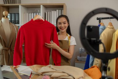 Kadın moda tasarımcısı, tasarımlarını müşterilerine canlı yayında izleterek müşterilerin satın alma kararlarını almalarına yardımcı olmak için tasarımlarının detaylarını anlatıyor.