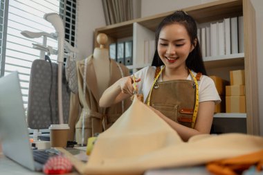 Güzel bir terzi, çeşitli dikiş malzemeleri, kumaş ve ipliklerle dolu bir stüdyoda en sevdiği zanaat üzerinde çalışıyor. Tasarımcı, terzi, moda, girişimci.
