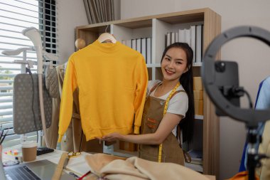 Kadın moda tasarımcısı, tasarımlarını müşterilerine canlı yayında izleterek müşterilerin satın alma kararlarını almalarına yardımcı olmak için tasarımlarının detaylarını anlatıyor.