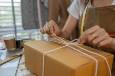 Güzel bir kadın giyim mağazası sahibi müşterilerle sohbet etmek için canlı yayın yapıyor ve ürünlerini müşterilere, paketlere, terzilere, tasarımcılara nakliyeye hazırlanmak için doxlara dolduruyor.