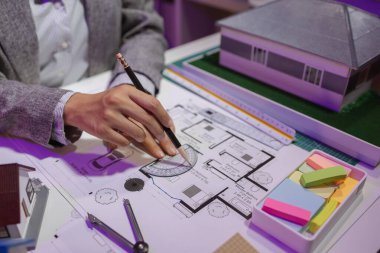 Güzel bir kadın mimar özel ofisinde çalışıyor çünkü kanunlara, mühendislere, ustabaşına ve müteahhitlere uygun olması için planların geliştirilmesine konsantre olması gerekiyor.