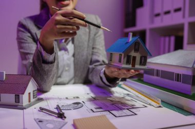 Tecrübeli bir kadın mühendis, özel ofisindeki bir ev modeline son bir çek veriyor. Planlara uyduğundan ve inşaatın bitiş tarihine yetiştiğinden emin olmak için.