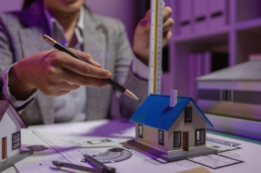 Tecrübeli bir kadın mühendis, özel ofisindeki bir ev modeline son bir çek veriyor. Planlara uyduğundan ve inşaatın bitiş tarihine yetiştiğinden emin olmak için.