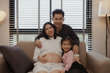 Güzel bir aile evlerinde birlikte vakit geçirir. Hamile bir anne, kocası ve kızıyla birlikte kanepede oturur ve hafta sonları birlikte mutlu vakit geçirir.