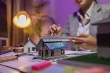 Tecrübeli bir kadın mühendis, özel ofisindeki bir ev modeline son bir çek veriyor. Planlara uyduğundan ve inşaatın bitiş tarihine yetiştiğinden emin olmak için.