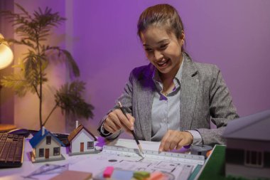 Güzel bir kadın mimar özel ofisinde çalışıyor çünkü kanunlara, mühendislere, ustabaşına ve müteahhitlere uygun olması için planların geliştirilmesine konsantre olması gerekiyor.