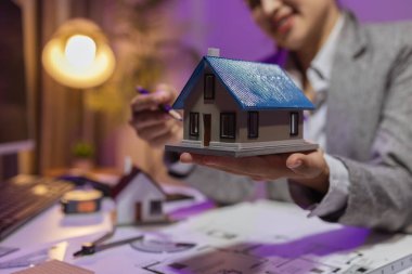 Tecrübeli bir kadın mühendis, özel ofisindeki bir ev modeline son bir çek veriyor. Planlara uyduğundan ve inşaatın bitiş tarihine yetiştiğinden emin olmak için.