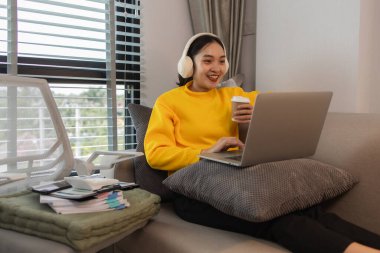 Bir kadın tatilini evinin oturma odasında, huzurlu ve mutlu bir şekilde geçirir çünkü kendisini rahat, yaşam tarzı, dairesi, kanepesi, koltuğu, kanepede hissettiren birçok etkinlik yapmıştır.