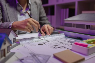 Güzel bir kadın mimar özel ofisinde çalışıyor çünkü kanunlara, mühendislere, ustabaşına ve müteahhitlere uygun olması için planların geliştirilmesine konsantre olması gerekiyor.