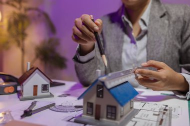 Tecrübeli bir kadın mühendis, özel ofisindeki bir ev modeline son bir çek veriyor. Planlara uyduğundan ve inşaatın bitiş tarihine yetiştiğinden emin olmak için.