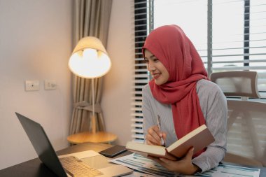 Müslüman bir kadın çalışan, özel ofisindeki bir şirkette mali ve muhasebe belgeleri üzerinde çalışıyor, tesettür, pazarlama, kadın müslüman şirket başkanı ofisinde çalışıyor.