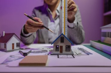 Tecrübeli bir kadın mühendis, özel ofisindeki bir ev modeline son bir çek veriyor. Planlara uyduğundan ve inşaatın bitiş tarihine yetiştiğinden emin olmak için.