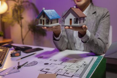 Tecrübeli bir kadın mühendis, özel ofisindeki bir ev modeline son bir çek veriyor. Planlara uyduğundan ve inşaatın bitiş tarihine yetiştiğinden emin olmak için.