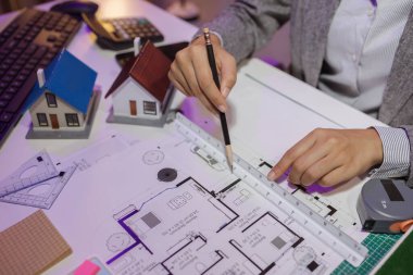 Güzel bir kadın mimar özel ofisinde çalışıyor çünkü kanunlara, mühendislere, ustabaşına ve müteahhitlere uygun olması için planların geliştirilmesine konsantre olması gerekiyor.