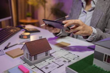 Tecrübeli bir kadın mühendis, özel ofisindeki bir ev modeline son bir çek veriyor. Planlara uyduğundan ve inşaatın bitiş tarihine yetiştiğinden emin olmak için.