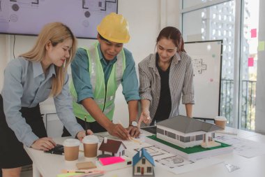 Mimar ve ekibi, bina modeli, mühendis ve takım çalışması ile planlardaki yapısal planların nasıl kontrol edileceği konusunda beyin fırtınası yapmak için inşaat yöneticisiyle görüşüyor.