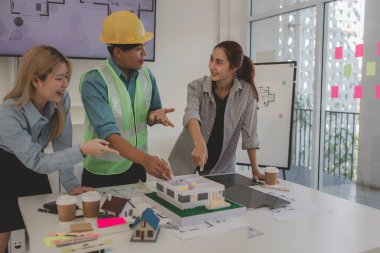 Mimar ve ekibi, bina modeli, mühendis ve takım çalışması ile planlardaki yapısal planların nasıl kontrol edileceği konusunda beyin fırtınası yapmak için inşaat yöneticisiyle görüşüyor.