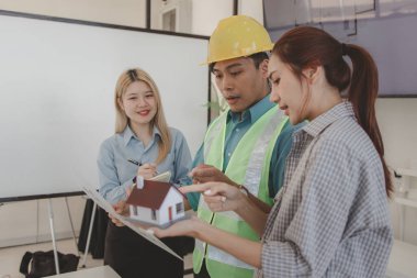 Mimar ve ekibi, bina modeli, mühendis ve takım çalışması ile planlardaki yapısal planların nasıl kontrol edileceği konusunda beyin fırtınası yapmak için inşaat yöneticisiyle görüşüyor.