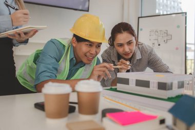 Mimar ve ekibi, bina modeli, mühendis ve takım çalışması ile planlardaki yapısal planların nasıl kontrol edileceği konusunda beyin fırtınası yapmak için inşaat yöneticisiyle görüşüyor.