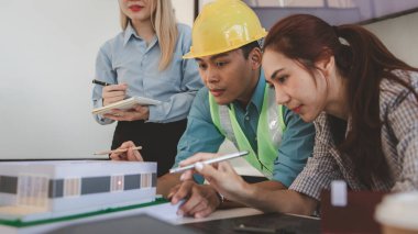 Mimar ve ekibi, bina modeli, mühendis ve takım çalışması ile planlardaki yapısal planların nasıl kontrol edileceği konusunda beyin fırtınası yapmak için inşaat yöneticisiyle görüşüyor.