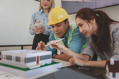 Mimar ve ekibi, bina modeli, mühendis ve takım çalışması ile planlardaki yapısal planların nasıl kontrol edileceği konusunda beyin fırtınası yapmak için inşaat yöneticisiyle görüşüyor.