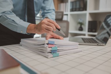 bir işadamı özel ofisinde oturuyor, bir girişimci özenle çalışıyor, baş muhasebeci yöneticilere bir toplantıda sunmak üzere belgeleri ve bütçe rakamlarını gözden geçiriyor